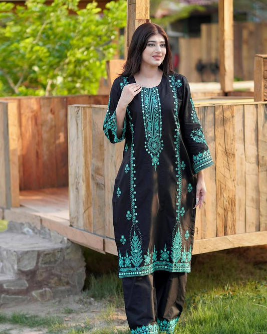 Woman wearing a black and green embroidered outfit standing outdoors.